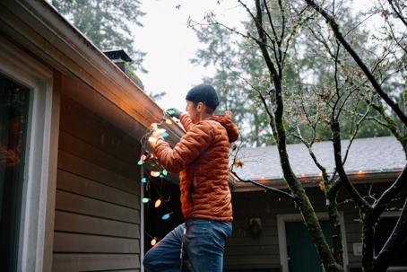 Man hanging up lights on house
